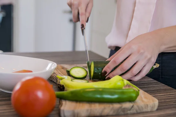 Mujer cortando verduras en su cocina. cortando pepino. Comida saludable y concepto vegetariano . — Foto de Stock