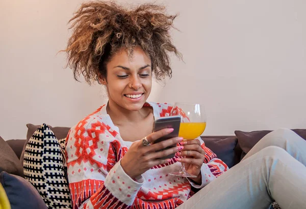 Афроамериканка отправляет текстовое сообщение на мобильный телефон - чернокожие отправляют ему прекрасное сообщение. Привлекательная молодая женщина с смартфоном и улыбкой — стоковое фото
