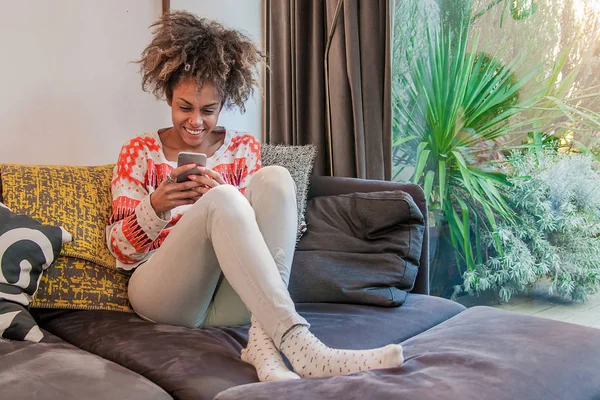 Personnes, technologie et concept de loisirs - gros plan de heureuse jeune femme afro-américaine textos sur smartphone à la maison — Photo