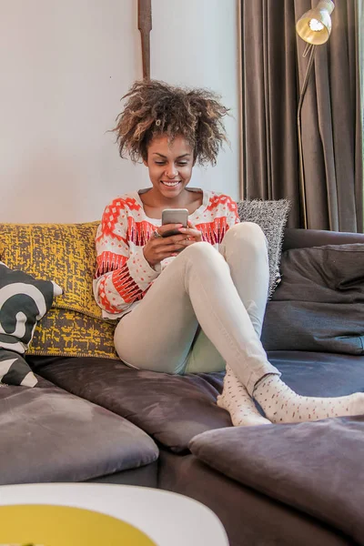 Άνθρωποι, τεχνολογίας και αναψυχής έννοια - στενή επάνω των γραπτών μηνυμάτων ευτυχισμένη αφροαμερικάνων νεαρή γυναίκα στο smartphone στο σπίτι — Φωτογραφία Αρχείου
