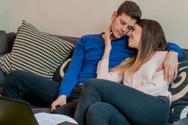 Sarılma ve oturma odası kanepe üzerinde oturan rahat bir çift. güzel çift rahatlatıcı. Kanepede aşık genç Çift