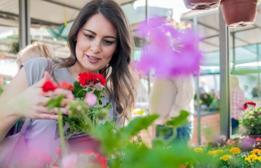 Bahçe Merkezi kil tencerede Sardunya tutan genç kadın. Genç kadın çiçek market bahçe merkezinde alışveriş