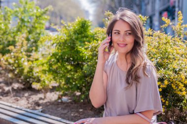 Şehrin akıllı telefonda konuşurken gülümseyen güzel genç kadın. teknoloji, iletişim, yaşam tarzı ve insanlar kavramı - gülümseyen genç kadın smartphone üzerinde şehir sokak arama