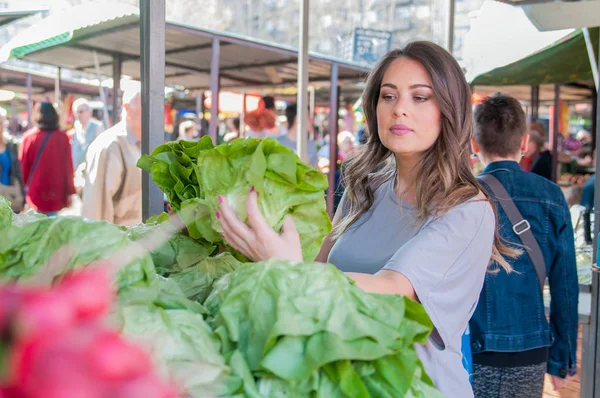 Young woman on the market. Happy young brunette  picking some ve — Stock Photo, Image