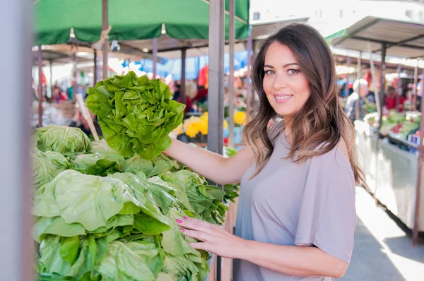 Portræt af smuk ung kvinde vælger grøn bladgrøntsager - Stock-foto