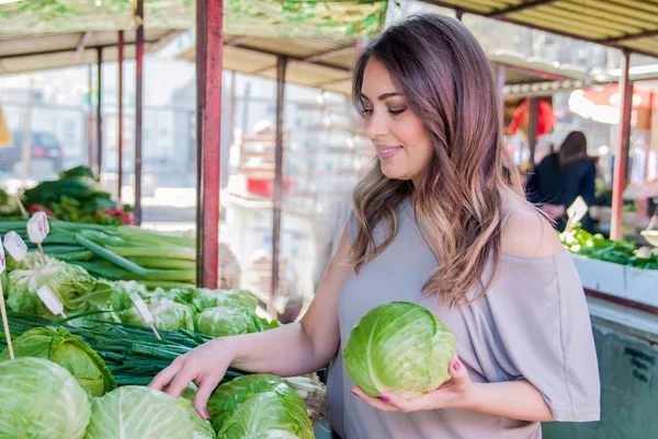 Raw food, veggie concept. Portrait of smiling good looking girl  in casual clothing holding cabbage in her hands. Healthy skin, glossy brown hair. — Stock Photo, Image