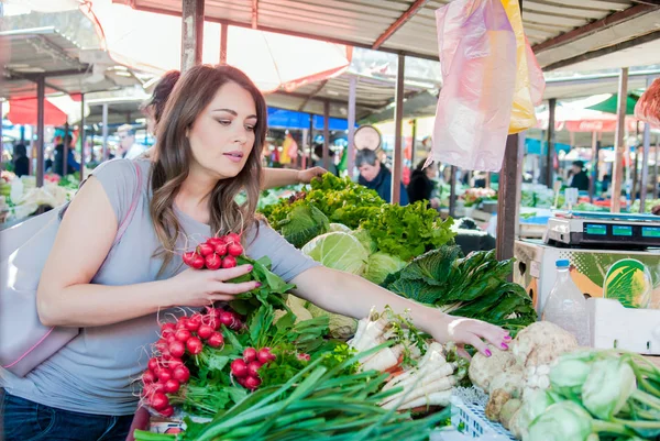 woman choosing fresh vegetables for measuring in grocery store.  Young woman buying vegetables at the green market.