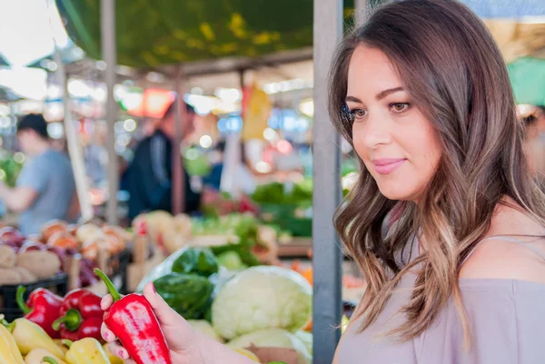 Glad woman choosing green and red paprika in supermarket Shopping. Woman choosing bio food fruit pepper paprica in green market — Stock Photo, Image