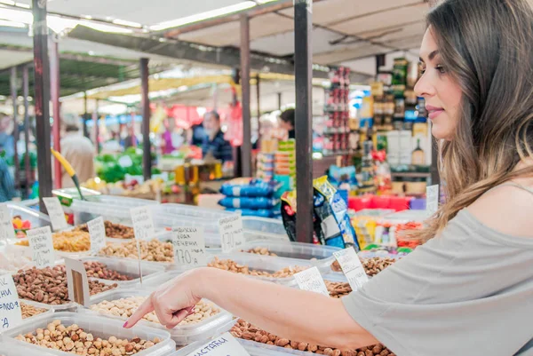 Vrouw kiest in de markt noten en gedroogde vruchten. Lachende jonge vrouw kiezen organische noten. vrouw kopen van verschillende noten gewichtspercentage in de kruidenierswinkel — Stockfoto