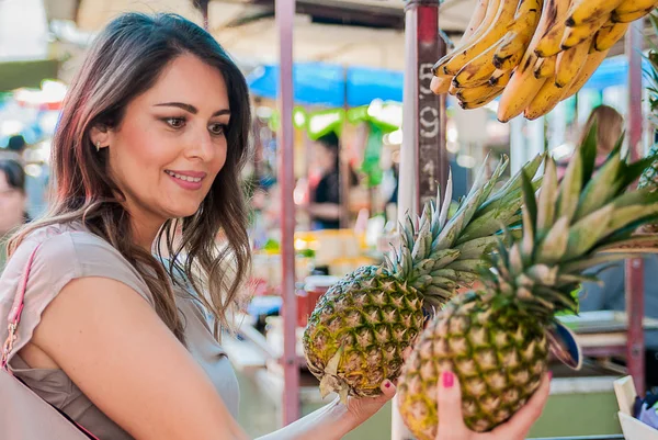 Mujer que elige la piña durante las compras en el mercado de verduras de frutas verde. Atractiva mujer de compras. hermosa joven recogiendo, eligiendo frutas, piñas . —  Fotos de Stock