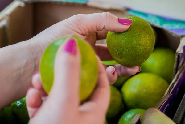 Sección media de la mujer comprando lima dulce en el supermercado. Mujer comprando frutas en el mercado verde orgánico. mujer eligiendo lima fresca —  Fotos de Stock