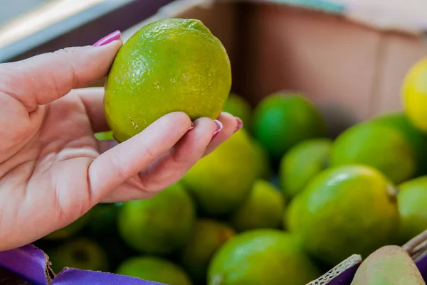 Sección media de la mujer comprando lima dulce en el supermercado. Mujer comprando frutas en el mercado verde orgánico. mujer eligiendo lima fresca —  Fotos de Stock