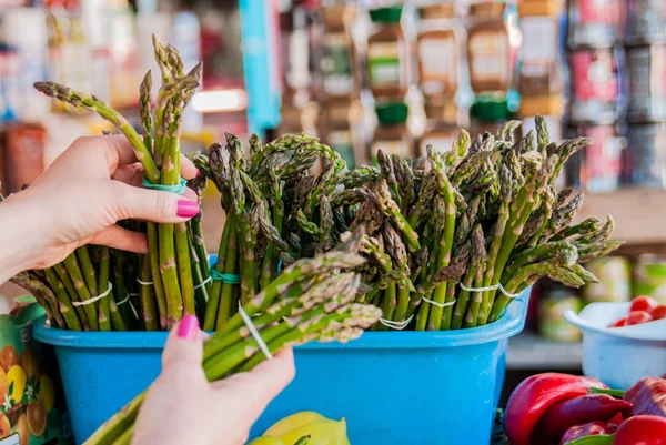 WOMAN WITH ASPARAGUS PurS. Жінка купує ASPARAGUS в супермаркеті. Свіжий зелений спаржевий овоч у руці жінки — стокове фото