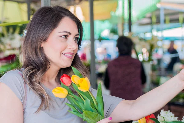 Mujer joven con hermoso ramo de tulipanes en la tienda de flores — Foto de Stock