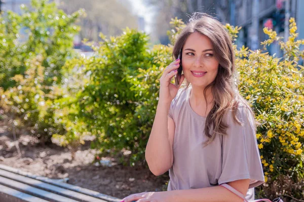 Sorrindo bela jovem mulher falando no telefone inteligente na cidade. tecnologia, comunicação, estilo de vida e conceito de pessoas - sorrindo jovem chamando no smartphone na rua da cidade — Fotografia de Stock