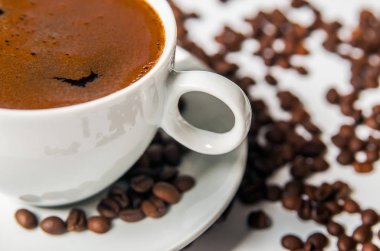 Beyaz arka planda kahve fincanı ve fasulye.. 