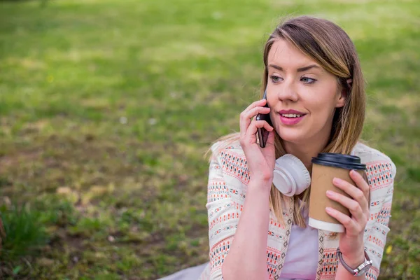 Mujer encantadora disfrutando de la conversación en el teléfono al aire libre. Chica con café para llevar — Foto de Stock