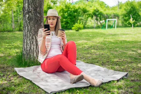 Mulher relaxante no parque e usando telefone inteligente . — Fotografia de Stock