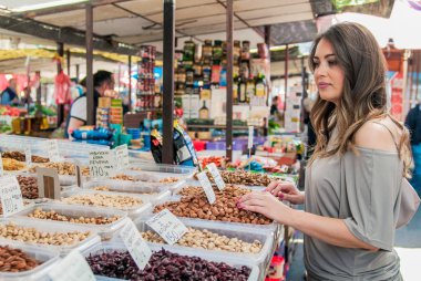 Genç ve güzel kadın satın alma fındık ve kuru meyve Çiftçi Market. Kadın alışveriş bakkal dükkanında ürünler seçme 