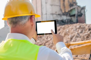 Sarı hardhat dijital tablet inşaat alanında, arkadan görünüm kullanma inşaat mühendisi portresi 