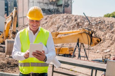 gülümseyen inşaat mühendisi inşaat alanında dijital tablet kullanarak sarı kask içinde portresi