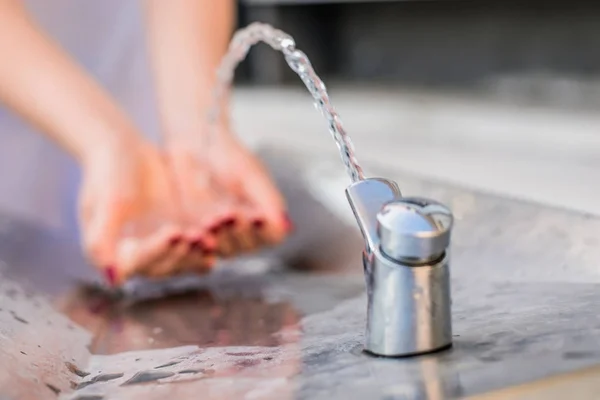 Woman washing hands in a city fountain — Stock Photo, Image