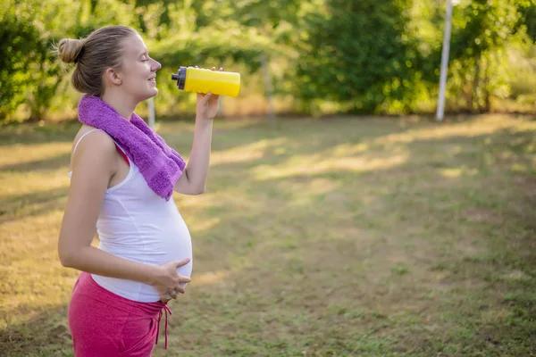 Kobieta w ciąży wody pitnej po fitness. — Zdjęcie stockowe