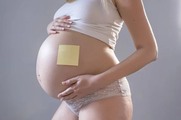 Pregnant woman with notepaper on her belly — Stock Photo, Image
