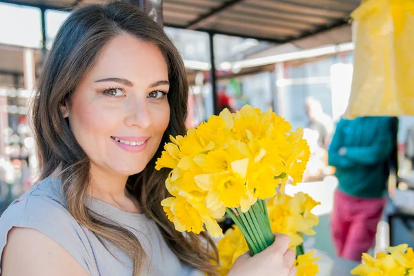Женщина наслаждается цветами на цветочном рынке — стоковое фото
