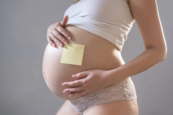 Těhotná žena s dopisní papír na břiše — Stock fotografie