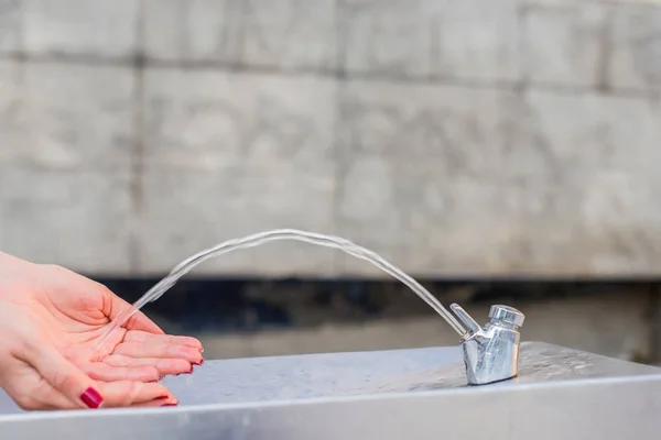 Woman washing hands in a city fountain — Stock Photo, Image