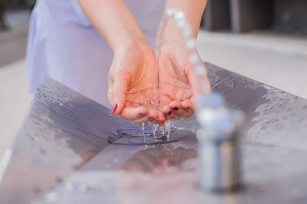 Woman washing hands in a city fountain — Stock Photo, Image