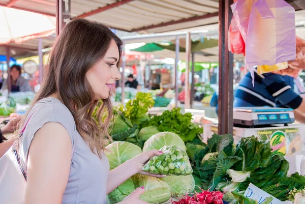 Woman buying vegetables at local market.