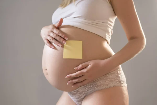 Gravid kvinna med brevpapper på hennes mage — Stockfoto