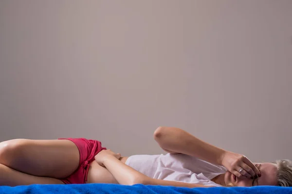 Жінка лежить в ліжку тримає живіт — стокове фото
