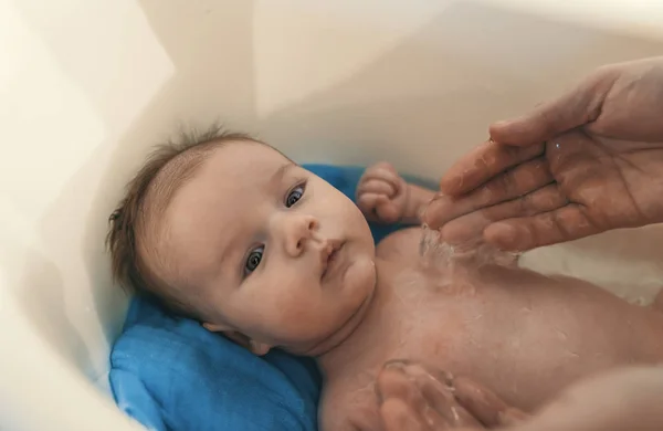 衛生と赤ちゃんのケア 白の小さなプラスチック製の赤ちゃんの浴槽で父入浴息子 — ストック写真