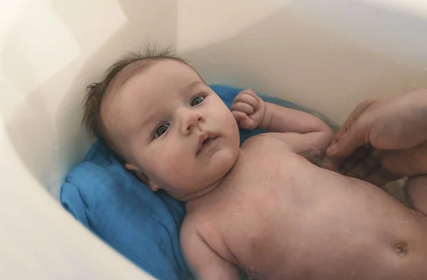 衛生と赤ちゃんのケア 白の小さなプラスチック製の赤ちゃんの浴槽で父入浴息子 — ストック写真
