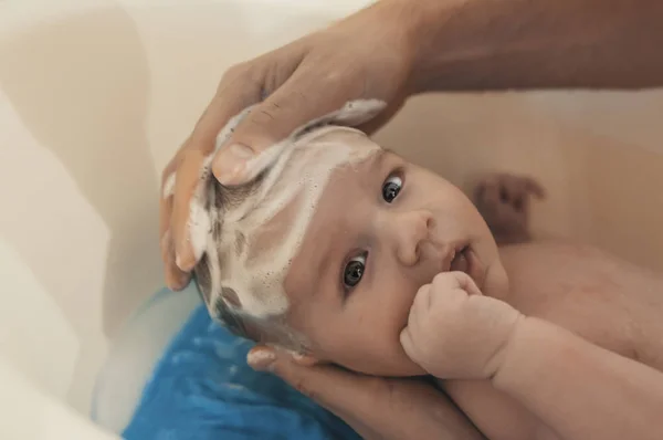 衛生と赤ちゃんのケア 白の小さなプラスチック製の赤ちゃんの浴槽で入浴息子は父 カメラ目線の赤ちゃん — ストック写真