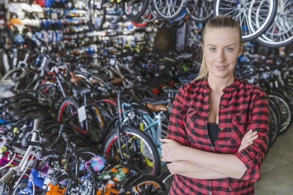 Happy female bike shop owner standing with folded arms