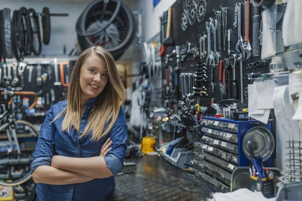 自行车修理厂的女技师肖像微笑和站立与折叠的胳膊 — 图库照片