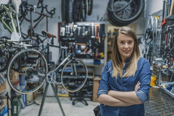 自行车修理厂的女技师肖像微笑和站立与折叠的胳膊 — 图库照片