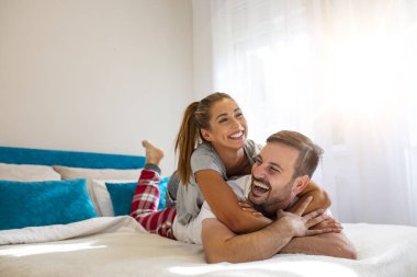 Yatak odasındaki resimde yatan mutlu adam ve kadın. Yatak odasındaki güzel genç çift yatakta yatıyor. Birlikte vakit geçirmenin tadını çıkarıyorum. Konforlu bir evde bir kızla bir erkeğin fotoğraf çekimi..