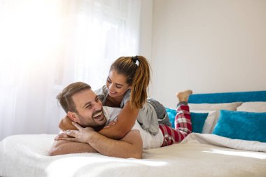 Evde birbirine aşık bir çift var. Birbirine aşık çift yatakta yatarken pijama giyip sarılıyorlar. Genç ve mutlu bir çift yatakta uzanıp eğleniyor. Sabahları bir çift. Kapat..