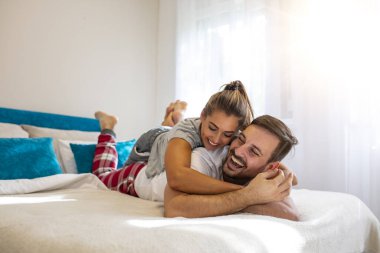 Yatakta mutlu genç bir çift. Teselli Kucağında Sevgi dolu bir çift. Güzel mutlu genç bir çift yatakta uzanıyor ve sarılıyorlar. Yatak odasındaki güzel çift yatakta yatıyor. Birlikte vakit geçirmekten zevk alıyorum..