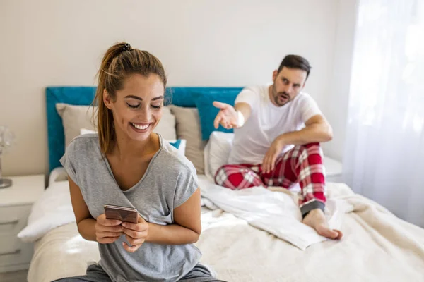 Jealous man looking in girlfriend phone while she texting a message, relationship problem. Husband is frustrated, upset while his internet addict wife is using mobile phone in social network