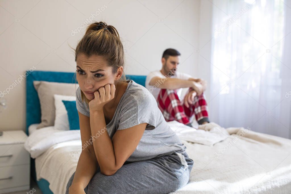 Image of Sad unhappy couple having problem in bed. Troubled woman expressing despair. Relationship Difficulties: Young couple having problems. Moody yong woman sitting at home