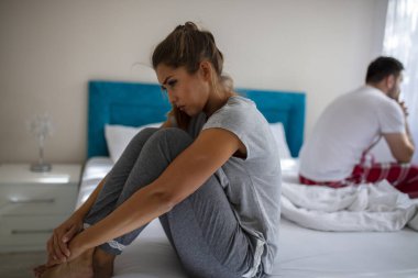 İlişki sorunları olan bir çift. İlişkilerinde sorunlar yaşayan genç bir çift. Genç bir kadın ve erkeğinin yatak odasında sorun yaşadıklarını gösteren bir resim. Bir sorunumuz var.