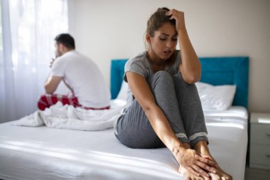 Çatışan bir çift yatakta üzgün duruyor. Stresli çift tartışıyor ve evlilik sorunları yaşıyor. Sorunları olan genç bir çift. Kadın ve erkek arasında anlaşmazlık var, yatakta sıkılmış genç bir çift.