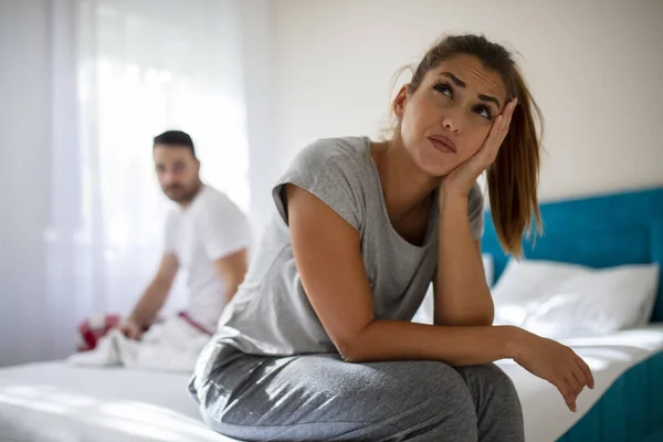 夫妻在床上有争吵和性问题 这对年轻夫妇性问题很困扰 我们有一个问题 年轻的心烦意乱的女孩坐在床沿上 面对着她的男朋友 — 图库照片