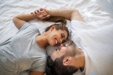 Güzel bir kadın, yatak odasındaki fotoğraftaki sevgilisine bakıyor. Yatakta birlikte yatan genç çiftin yukarıdan yakın çekimleri. Birbirine aşık romantik bir çift sabahları yatakta birbirine sarılan genç çiftin üst düzey görüntüsü..